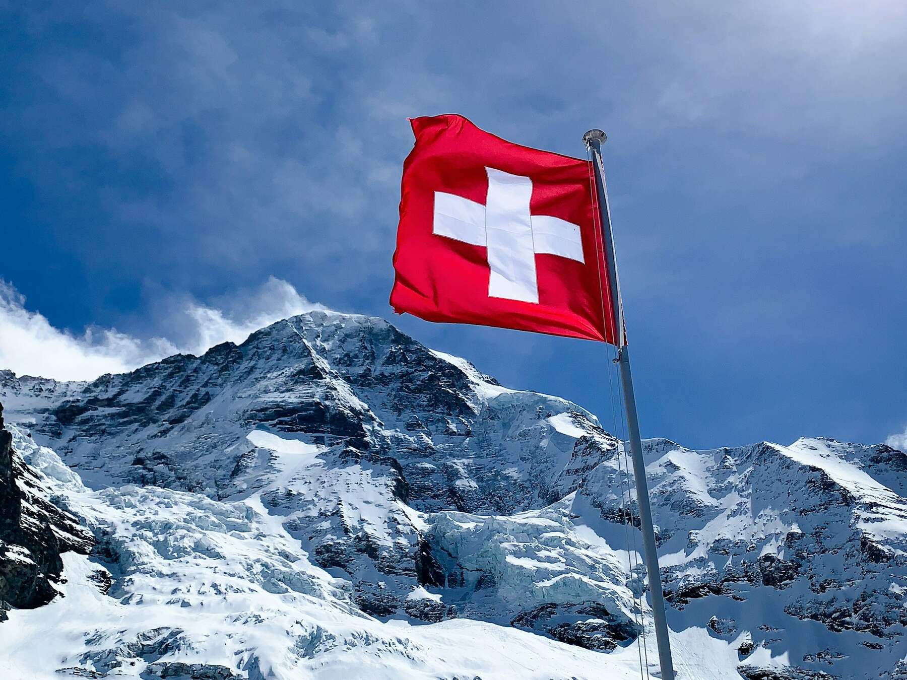 Schweizerfahne vor verschneiten Alpen